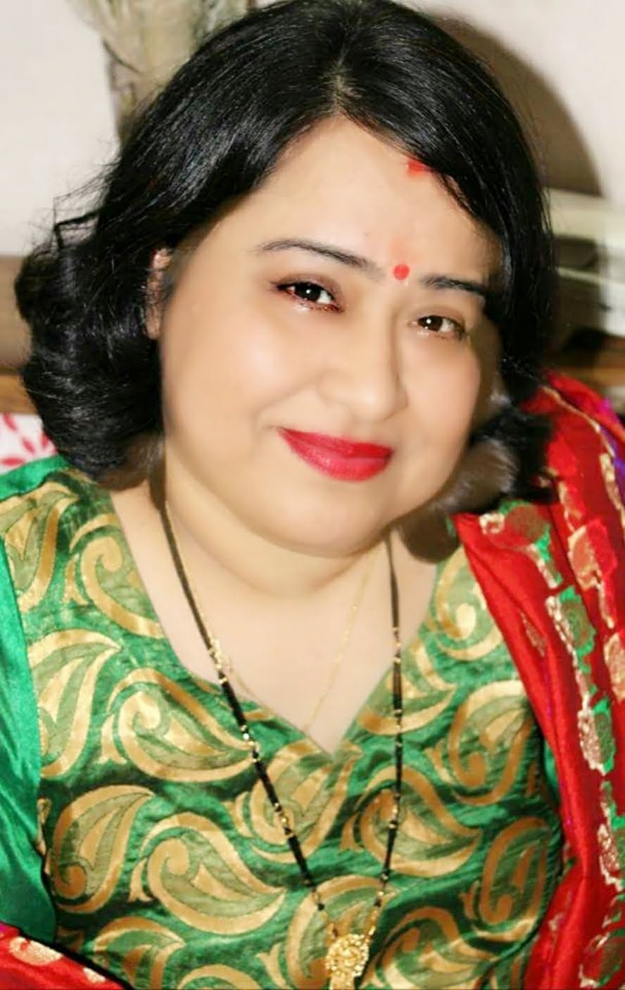 Dr Abha Khetarpal, wearing a traditional Indian salwar suit in green and red combination and jewelry and red bindi on her forehead.